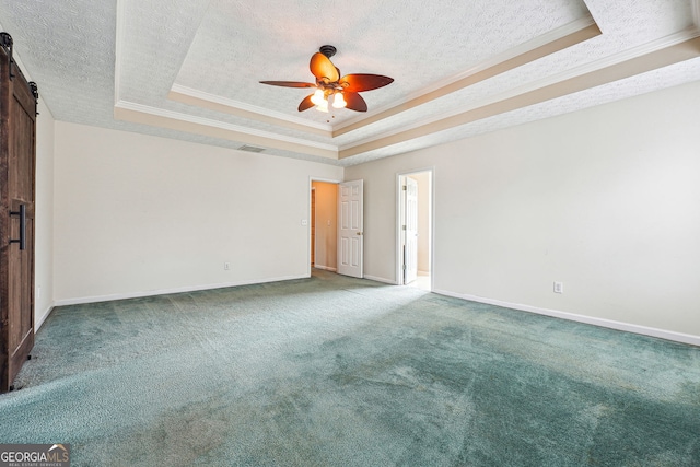 spare room with carpet, a barn door, a raised ceiling, and ornamental molding