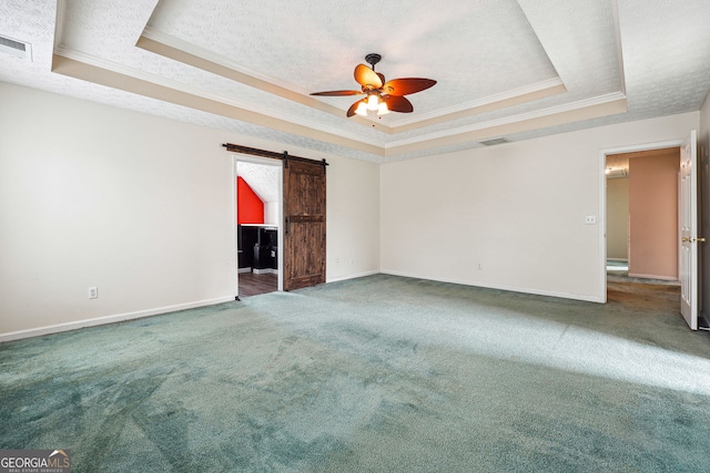carpeted spare room featuring visible vents, crown molding, baseboards, a tray ceiling, and a ceiling fan