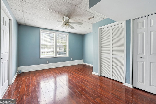 unfurnished bedroom with a ceiling fan, a paneled ceiling, visible vents, wood finished floors, and baseboards