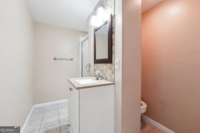 bathroom with a shower with shower door, vanity, tile patterned flooring, toilet, and tasteful backsplash