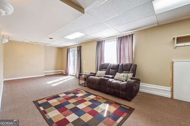 carpeted living room with baseboards and a drop ceiling