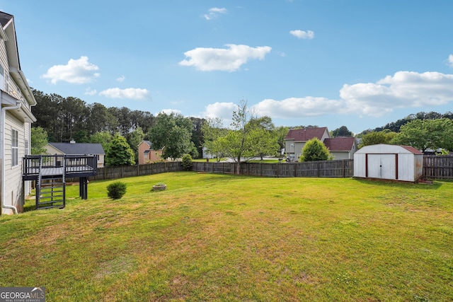 view of yard with an outdoor structure, a wooden deck, a fenced backyard, a storage unit, and stairway