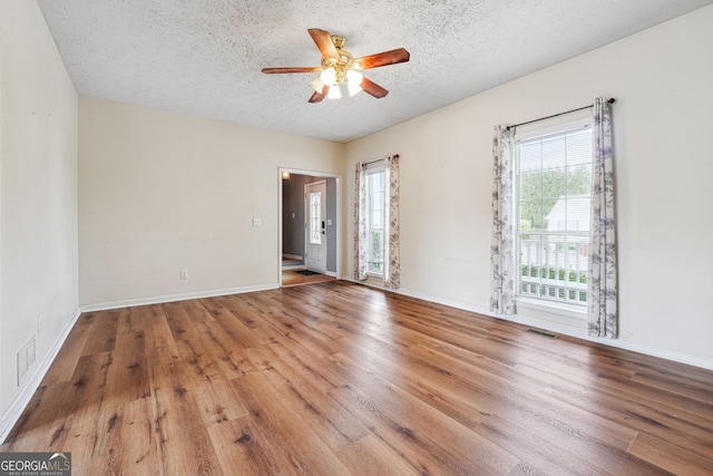 unfurnished room featuring a textured ceiling, ceiling fan, visible vents, and wood finished floors
