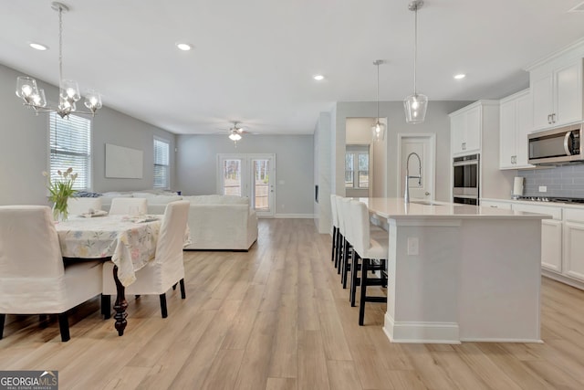kitchen with appliances with stainless steel finishes, open floor plan, light wood-style floors, and a sink