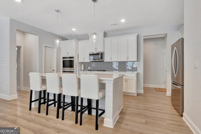 kitchen featuring decorative backsplash, appliances with stainless steel finishes, light countertops, light wood finished floors, and baseboards
