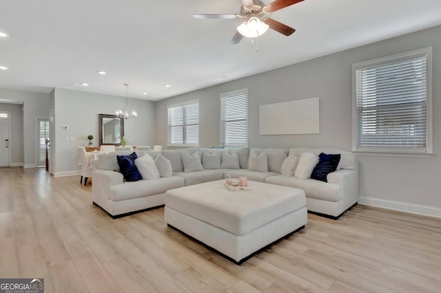 living room with baseboards, recessed lighting, ceiling fan with notable chandelier, and light wood-style flooring