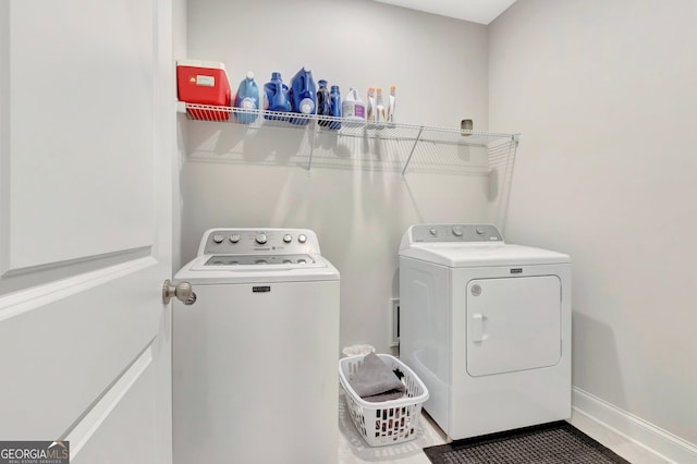 clothes washing area featuring baseboards, laundry area, and washing machine and dryer
