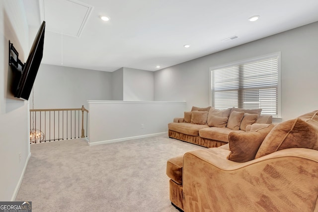 living area featuring baseboards, visible vents, attic access, and light colored carpet