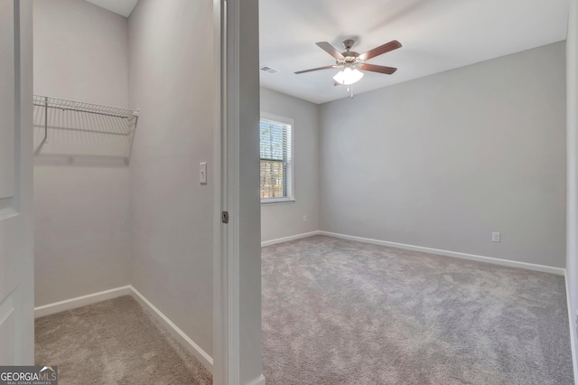 interior space featuring baseboards, visible vents, ceiling fan, and carpet flooring