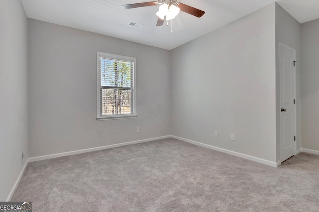 carpeted empty room with baseboards, visible vents, and a ceiling fan