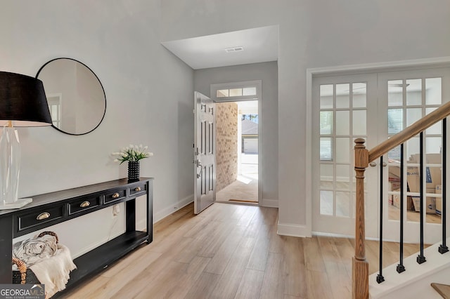 entrance foyer with visible vents, stairway, light wood-type flooring, and baseboards