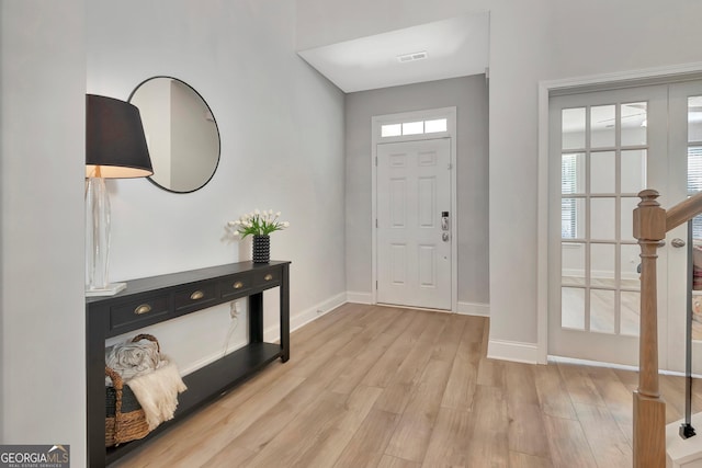 foyer entrance featuring visible vents, light wood finished floors, and baseboards