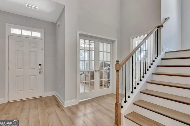 entryway with stairs, visible vents, light wood-style flooring, baseboards, and french doors