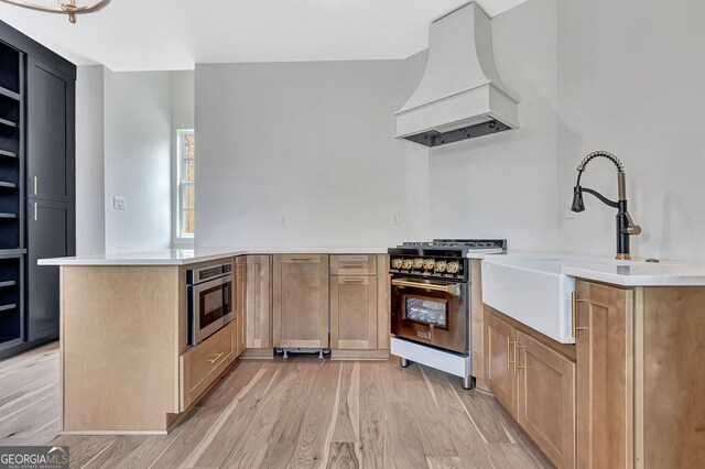 124 Morgan St, Senoia, GA 30276 - kitchen with custom exhaust hood, high end stainless steel range, a peninsula, light wood-type flooring, and a sink
