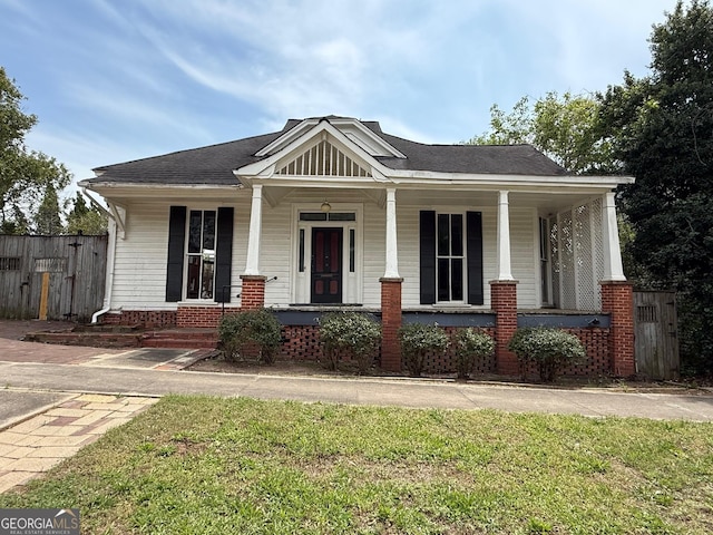 bungalow-style house featuring fence, a porch, and a front lawn