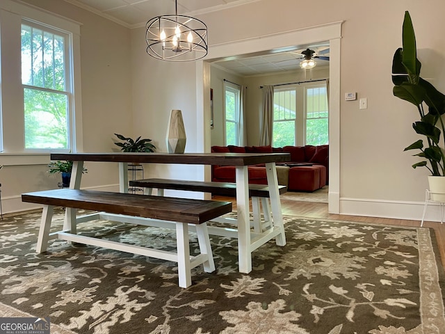 dining space featuring crown molding, ceiling fan with notable chandelier, baseboards, and a healthy amount of sunlight