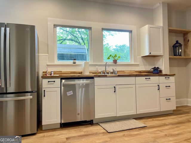 kitchen featuring appliances with stainless steel finishes, plenty of natural light, open shelves, and white cabinets