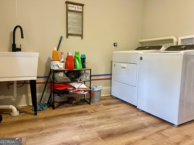 clothes washing area with a sink, baseboards, washer and dryer, wood finished floors, and laundry area