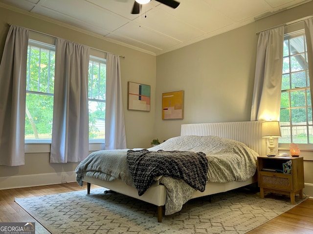 bedroom featuring baseboards, wood finished floors, a ceiling fan, and ornamental molding