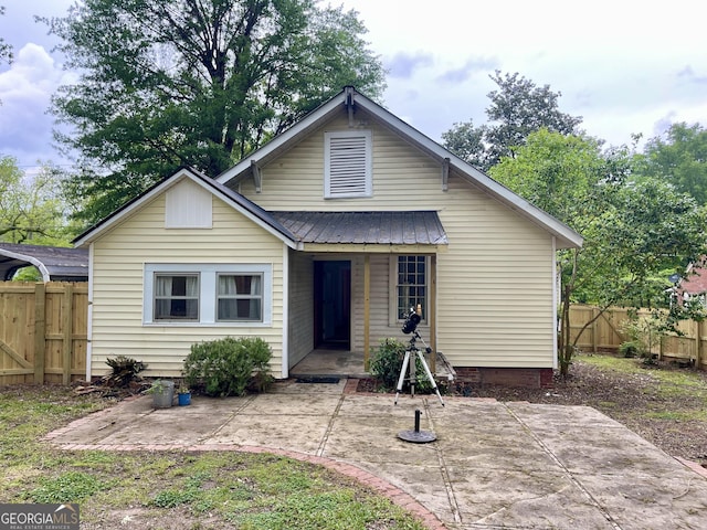 view of front of home with covered porch, fence private yard, metal roof, and a patio area