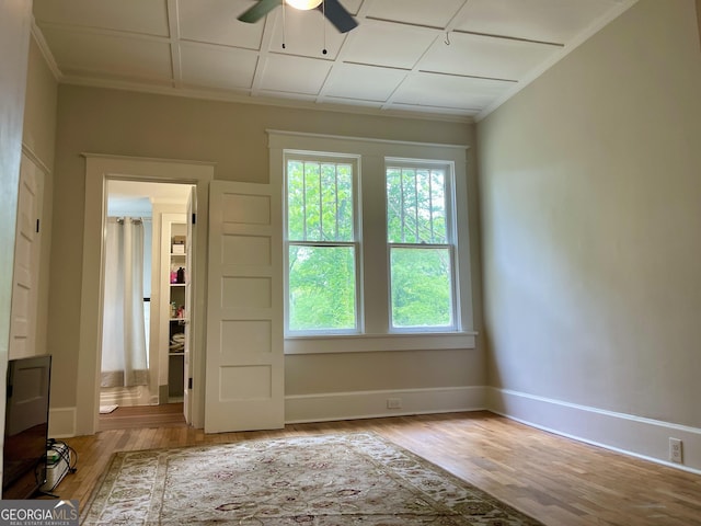 spare room featuring ornamental molding, a ceiling fan, light wood finished floors, and baseboards