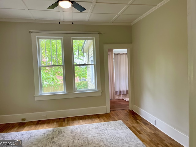 spare room featuring crown molding, ceiling fan, wood finished floors, and baseboards