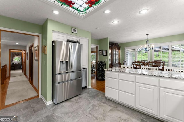 kitchen featuring a chandelier, white cabinetry, baseboards, a textured ceiling, and stainless steel fridge with ice dispenser