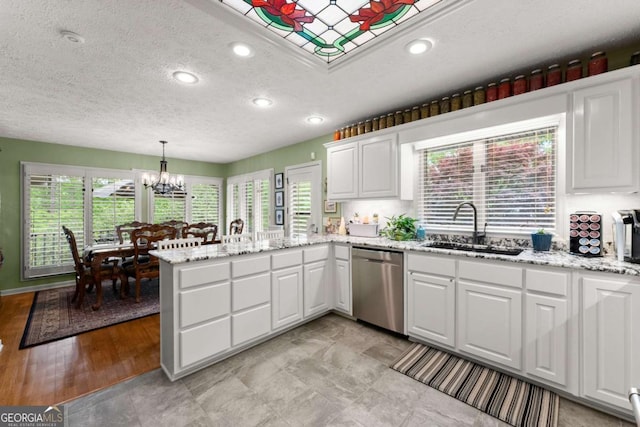 kitchen with a sink, a peninsula, white cabinetry, a textured ceiling, and dishwasher