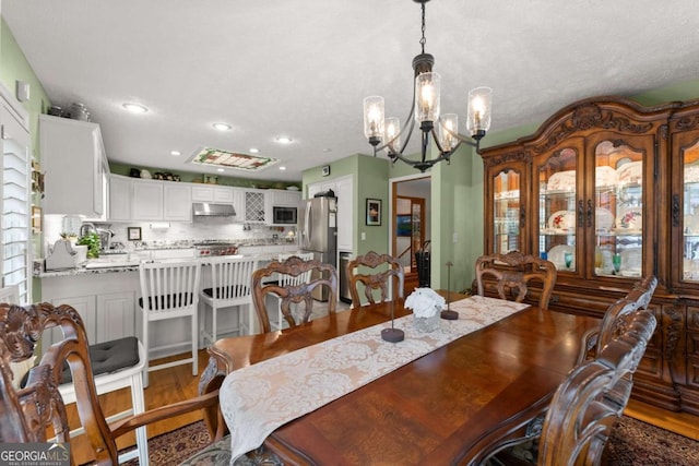 dining space with a chandelier, recessed lighting, and wood finished floors