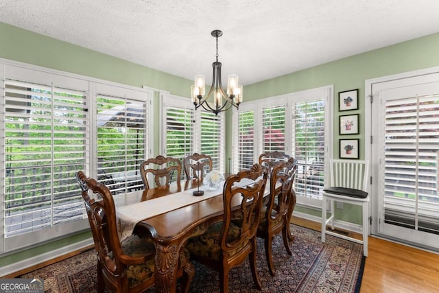 dining room with a chandelier, wood finished floors, and a textured ceiling