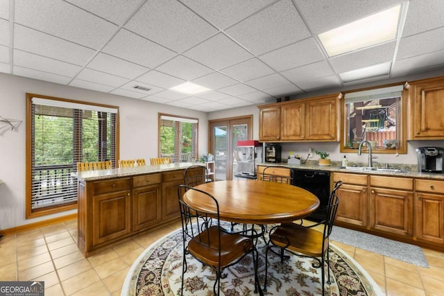 kitchen featuring light tile patterned floors, visible vents, a paneled ceiling, and brown cabinetry