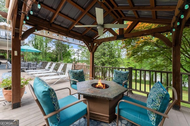 wooden terrace featuring a ceiling fan, a gazebo, and an outdoor fire pit