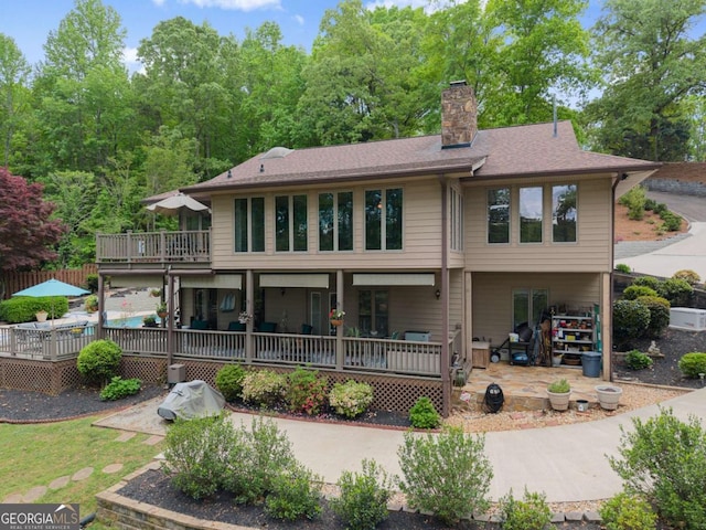 back of house featuring a chimney, a patio, and a deck