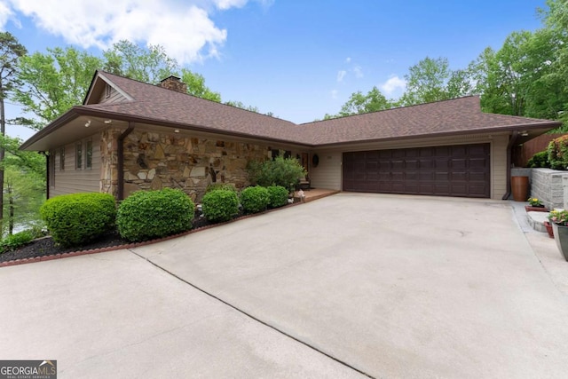 view of front of home featuring a chimney, an attached garage, driveway, stone siding, and roof with shingles