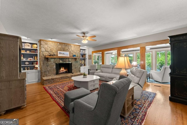 living room featuring a ceiling fan, a healthy amount of sunlight, a textured ceiling, and a fireplace