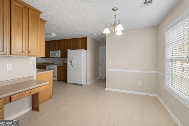kitchen featuring white appliances, a chandelier, decorative light fixtures, light countertops, and visible vents