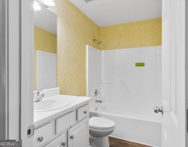 bathroom featuring vanity, bathing tub / shower combination, toilet, a textured ceiling, and wood finished floors