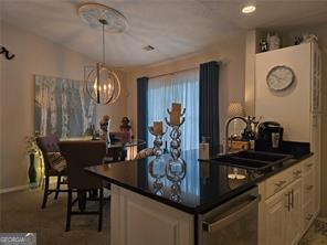 6193 Charring Cross Ct, Lithonia, GA 30058 - kitchen with dishwasher, dark countertops, a chandelier, a sink, and baseboards