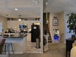 kitchen with stainless steel microwave, range, fridge, dark countertops, and white cabinets