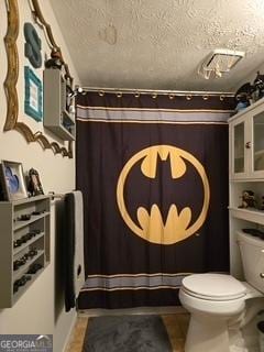 bathroom featuring toilet, a textured ceiling, a shower with curtain, and tile patterned floors