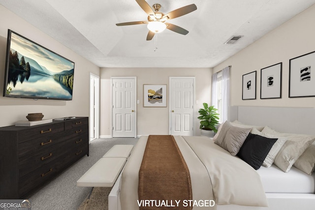 carpeted bedroom featuring baseboards, visible vents, ceiling fan, and a tray ceiling
