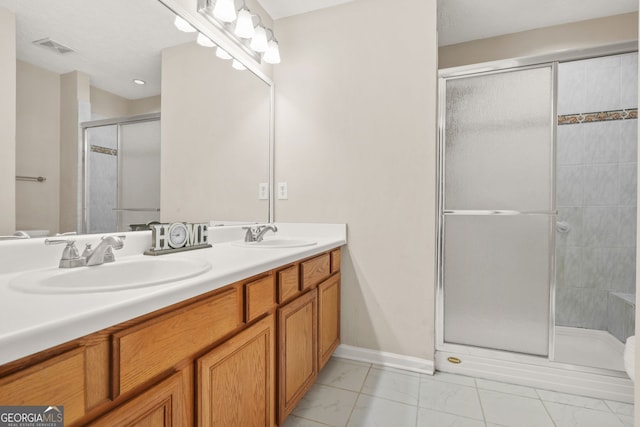 full bath with visible vents, a shower stall, double vanity, and a sink