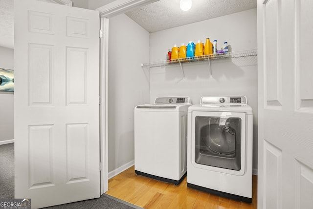 washroom featuring a textured ceiling, independent washer and dryer, baseboards, light wood finished floors, and laundry area