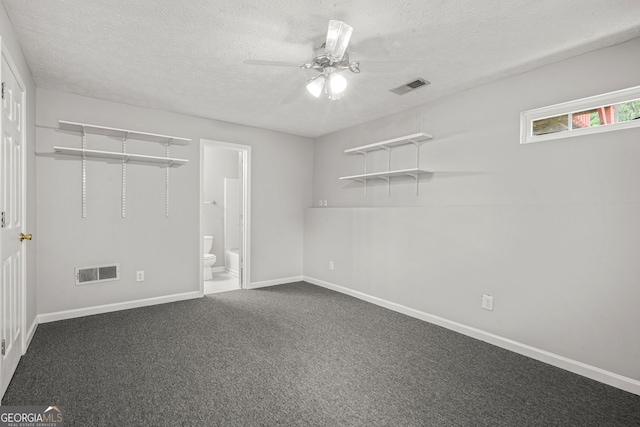 unfurnished bedroom featuring baseboards, visible vents, dark carpet, and a textured ceiling