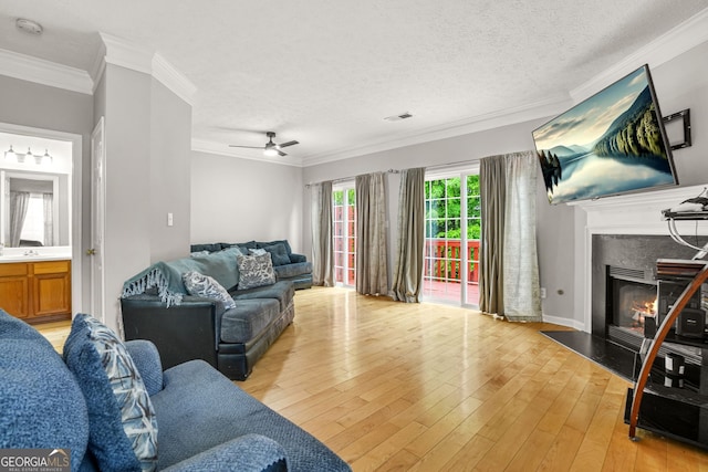 living area with visible vents, ornamental molding, a ceiling fan, and a fireplace with flush hearth