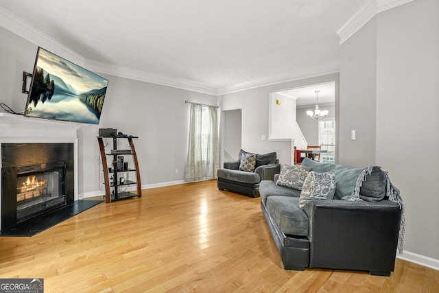 living room with a fireplace with flush hearth, a chandelier, crown molding, baseboards, and hardwood / wood-style flooring