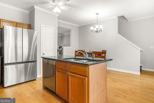 kitchen featuring stainless steel appliances, an island with sink, light wood-style floors, and a sink