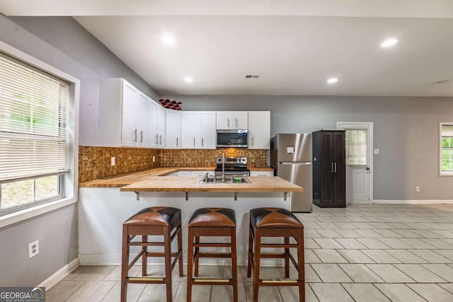 4240 Cascade Rd SW, Atlanta, GA 30331 - kitchen featuring tasteful backsplash, stainless steel appliances, a peninsula, and butcher block counters