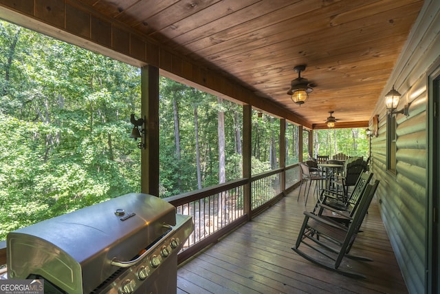deck with grilling area and a forest view
