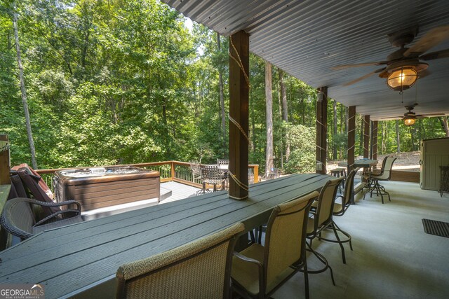 deck featuring outdoor dining area, a ceiling fan, and a forest view